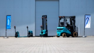 Baoli Produtksortiment blaue Fahne links, drei Hubwagen, ein Gabelstapler, weisse Fahne rechts 