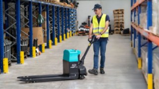 Baoli Niederhubwagen KBP 15L in Bedienung eines Lagermitarbeiters zwischen Lagerregalen 