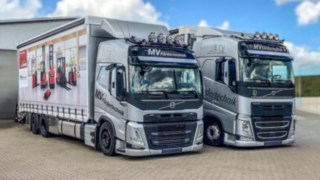 Sattelzugtieflader geschlossen links für Großtransport, Solo-Lkw rechts geschlossen mit Werbeplane