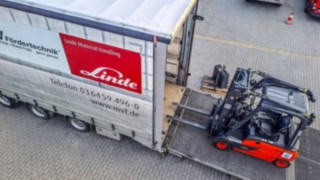 links Lkw MV Fördertechnik mit abgelassener Laderampe darauf ein Gabelstapler rechts