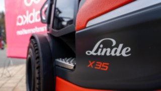 Nahaufname vom Linde X35 seitlich, nur der Einstieg und der Reifen sind zu sehen. Im Hintergrund die Fahne von CABKA.
