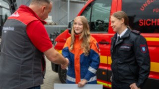 Nachwuchsmitgliederin der Jugendfeuerwehr Blankenhain übernimmt Spendenscheck  Geschäftsführer R. Müller gibt Nachwuchsmitgliederin der Jugendfeuerwehr Blankenhain die Hand