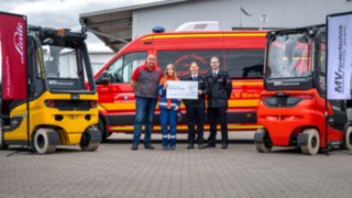 Links und rechts Stapler in der Mitter der Geschäftsführer dann Jugendfeuerwehr Mitgliederin, Jugendfeuerwehrwartin und Wehrleiter, dahinter der ELW der Feuerwehr Blankenhain