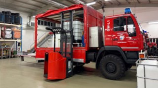 Kammeradinnen und Kameraden der Feuerwehr Wurzbach mit Hochhubwagen im Hintergrund der Gerätewagen