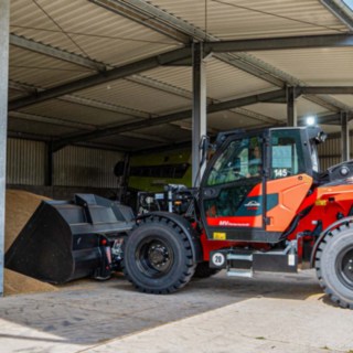 Linde YH60 Teleskoplader links bei Aufnahme von Weizen in offener Halle links