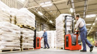 Mitarbeiter im Lager beim bedienen von Hochhubwagen die Säcke auf Paletten transportieren