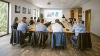 Schulungsraum mit sitzenden Teilnehmern an Tischen in der theoretische Ausbildung zum Staplerfahrer 