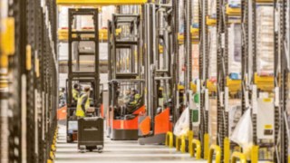 Logistikhalle mit Hochregallagern in dem sich Schubmaststapler bewegen mit Lagertechnikgeräteführern