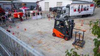 StaplerCup Qualifier Parcours Abwasserrohr Stapler in Parcours, Rings rum Absperrgatter und Publikum, im Hintergrund die Werktstatthalle und der LKW