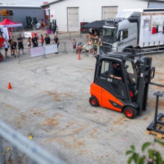 StaplerCup Qualifier Parcours Abwasserrohr Stapler in Parcours, Rings rum Absperrgatter und Publikum, im Hintergrund die Werktstatthalle und der LKW