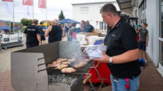 Verpfegung beim StaplerCup Qualifier 2025 Bratwurstrost links mit Bratgut die von einem Mitarbeiter rechts stehend gewendet wird