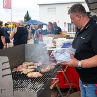 Verpfegung beim StaplerCup Qualifier 2025 Bratwurstrost links mit Bratgut die von einem Mitarbeiter rechts stehend gewendet wird
