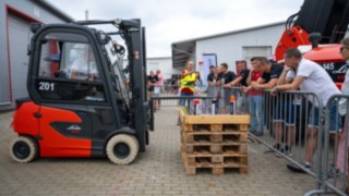 Mini-Fässer Parcours Action mit dem Gabelstapler Roter Linde Stapler links im Parcours, rechts hinter den Absprerrungen die Teilnehmer und Zuschauer