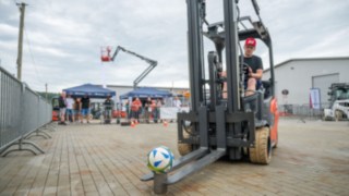 Gabelstapler rechts hat Fußball auf den Gabelzinken 