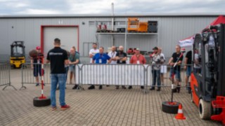 links der Schiedsrichter mit Warnweste, rechts etwas weiter entfernt die Teilnehmer hinter den Absprerrungen 