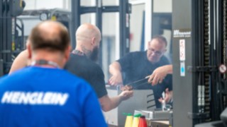 Staplerfahrer im Vordergrund links, im Hintergrund der Bratwurstrost 